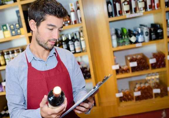 Wine store owner checking clipboard for inventory