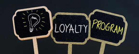 3 chalkboards, first with a lightbulb drawing, second says LOYALTY, third says PROGRAM 