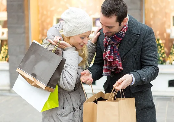 A man and a woman looking at their shopping bags and smiling