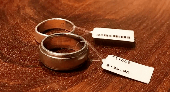 2 metal rings on a wooden desk, with prices tags attached
